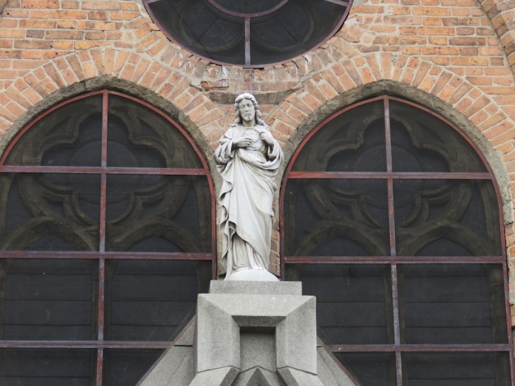 Statue up high in the front of the church