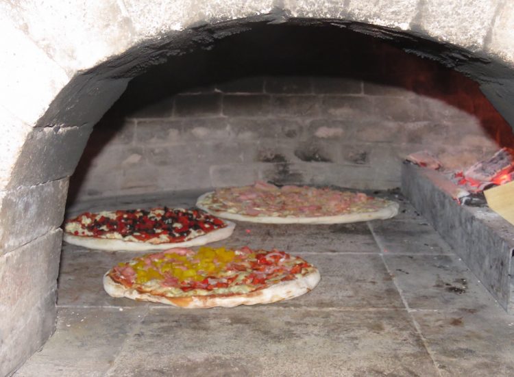 Pizzas being cooked in the brick oven