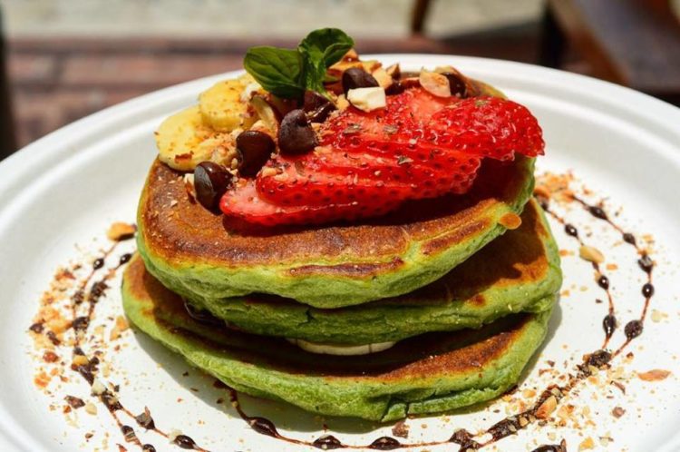 A nice stack of avocado pancakes with fruit on top