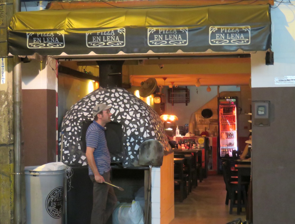 Pizza en Leña, with the brick oven in front and owner cooking
