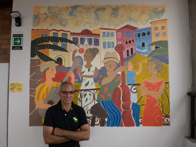Joel, the owner, in front of a painting by one of his guests
