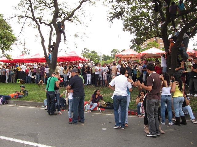 Couples dance in the street while others climb trees for a better view of the parade.