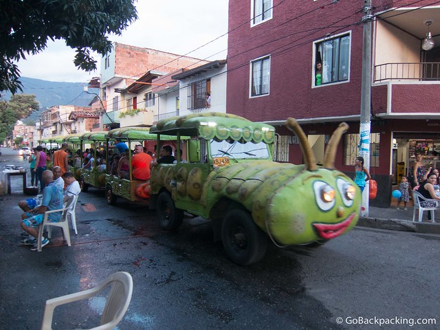 A jeep disguised as a caterpillar pulls kids through the neighborhood streets