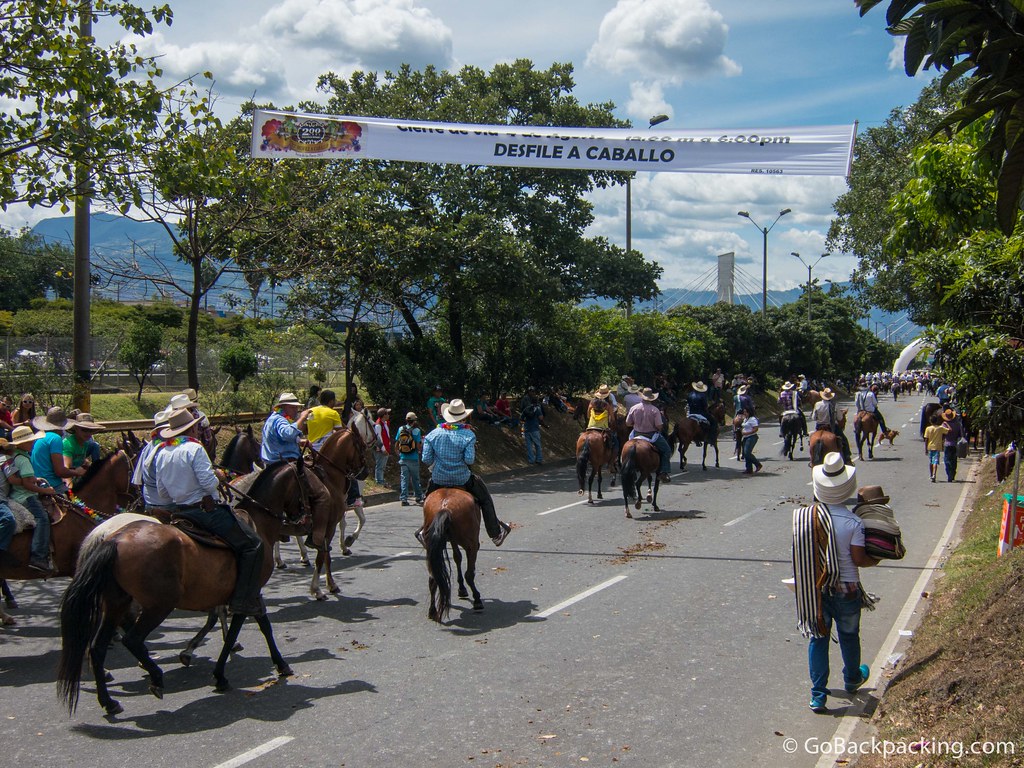 A banner hangs over the parade route, announcing the horse parade runs from 12pm to 6pm